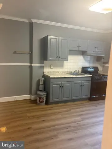 a kitchen with kitchen island granite countertop a sink cabinets and wooden floor