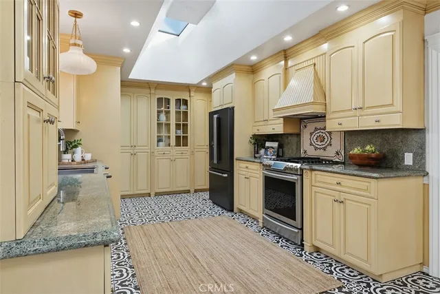 a kitchen with stainless steel appliances granite countertop a refrigerator a stove and a sink