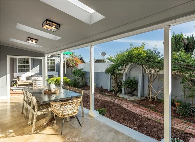 a view of a patio with table and chairs potted plants and floor to ceiling window