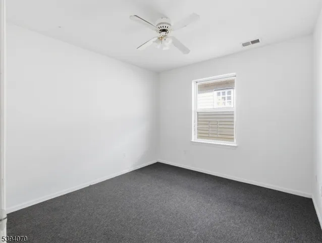 an empty room with a window and a ceiling fan
