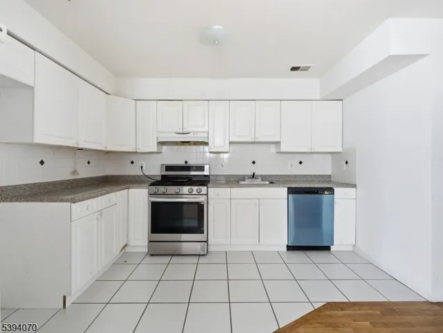 a kitchen with a sink a stove top oven and white cabinets
