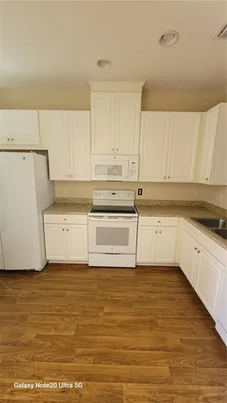 a white kitchen with granite countertop white cabinets and white appliances