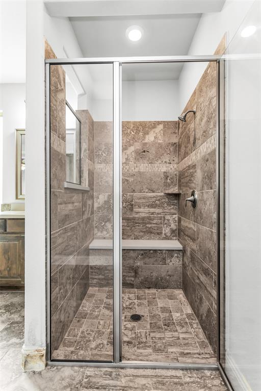 6333 Hall Road Frisco, TX 75034 - Photo 22 of 38 Glass-enclosed shower featuring natural stone-look tile, a built-in bench, recessed lighting, and a chrome showerhead