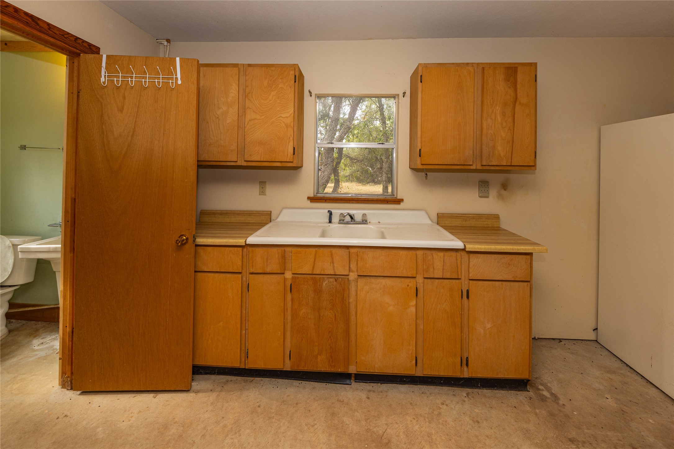2501 Fischer Store Road Wimberley, TX 78676 - Photo 15 of 23 Kitchen area featuring wood-finish cabinetry, a double basin sink, and a window providing exterior light