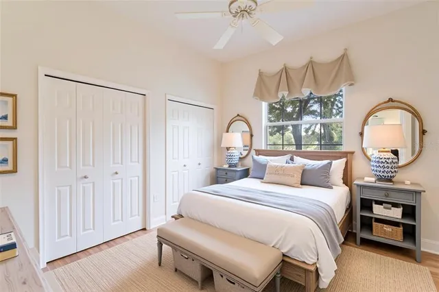 a bedroom with a bed a dresser and potted plants with the wooden floor