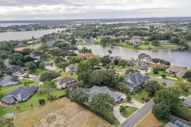 an aerial view of city and lake with trees