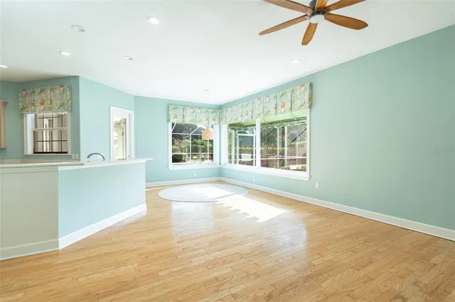 an empty room with wooden floor fan and windows