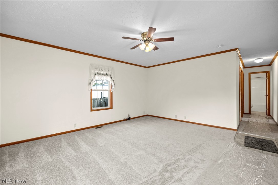 35157 Center Ridge Road, Unit 92 North Ridgeville, OH 44039 - Photo 19 of 40 Spacious room featuring neutral carpet, wood trim accents, a ceiling fan with integrated lighting, and a single window