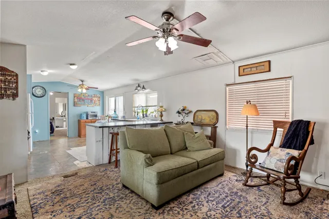 a living room with furniture a flat screen tv and a refrigerator