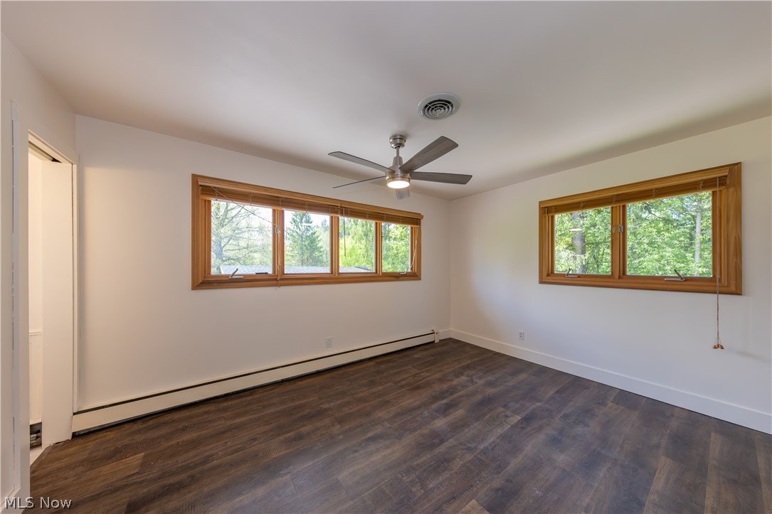 7969 Dines Road Novelty, OH 44072 - Photo 19 of 48 Spacious bedroom featuring wood-finish flooring, two large windows with natural wood trim, and a ceiling fan with integrated lighting