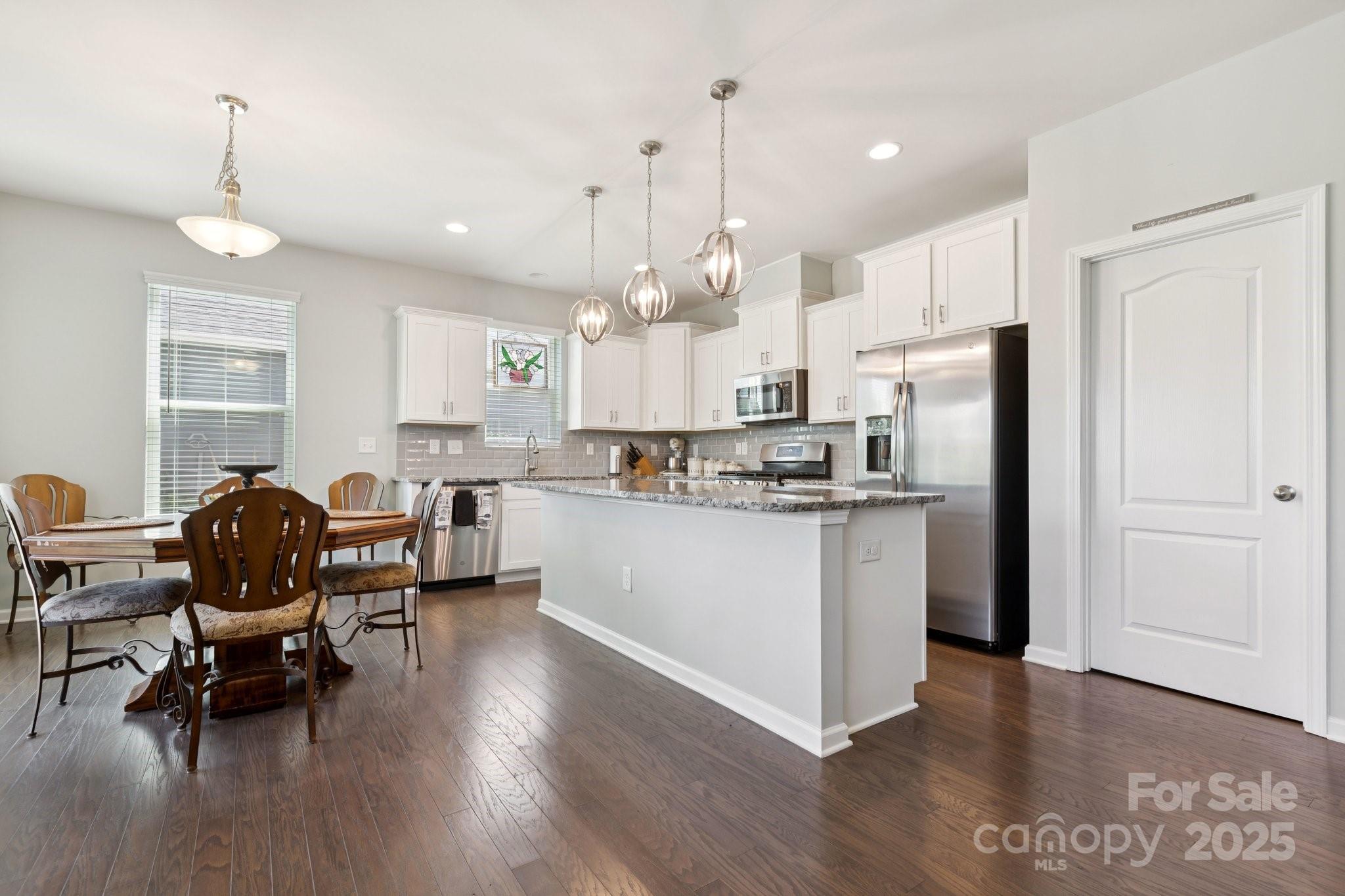 4236 Merrivale Drive Lancaster, SC 29720 - Photo 12 of 48 a kitchen with stainless steel appliances kitchen island granite countertop a table chairs refrigerator and microwave