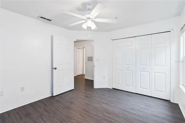 an empty room with wooden floor and a ceiling fan