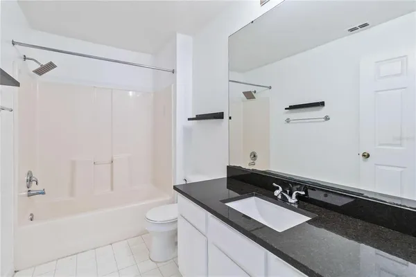 a bathroom with a granite countertop sink toilet a large mirror and shower
