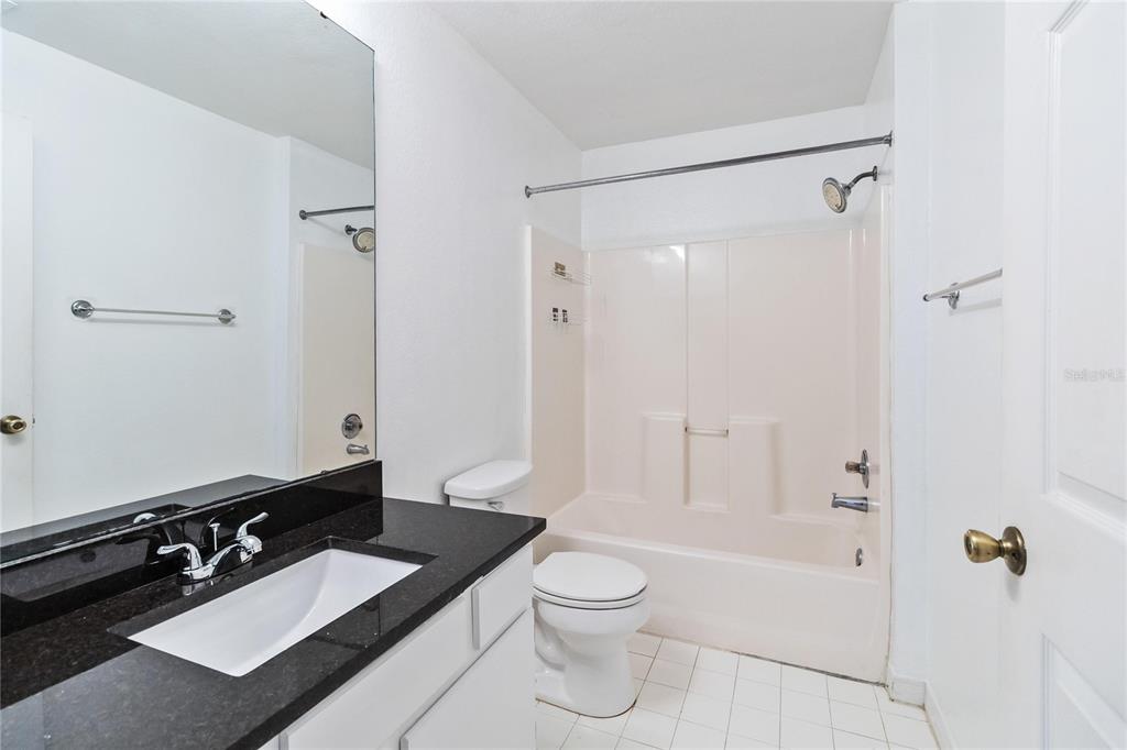 5459 Vineland Road, Unit 4208 Orlando, FL 32811 - Photo 23 of 29 a bathroom with a granite countertop sink toilet a mirror a vanity and shower