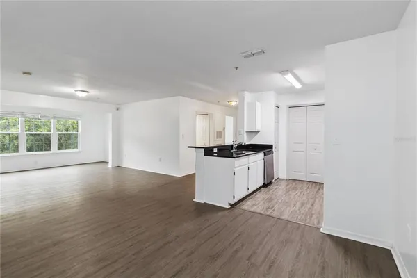 a large white kitchen with wooden floors and white cabinets