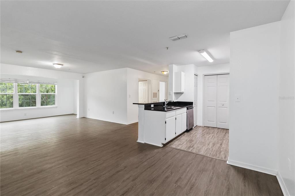 5459 Vineland Road, Unit 4208 Orlando, FL 32811 - Photo 6 of 29 a large white kitchen with wooden floors and white cabinets