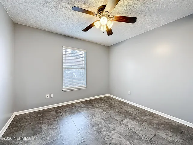 an empty room with a window and a fan