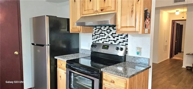 a kitchen with stainless steel appliances granite countertop a refrigerator and a stove