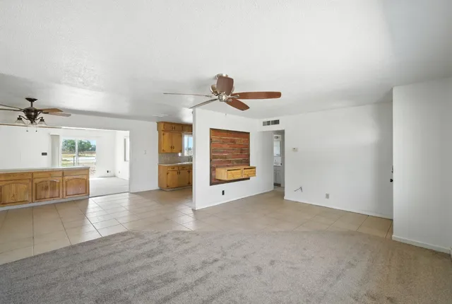 a view of an empty room with a window and kitchen view
