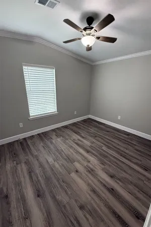 an empty room with wooden floor ceiling fan and windows