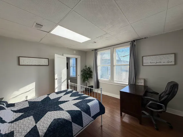 a view of an empty room with a window and wooden floor