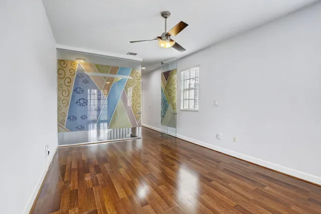 a view of empty room with wooden floor and fan