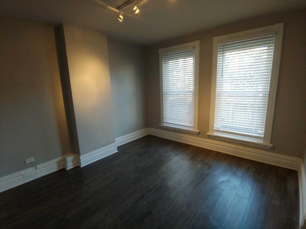 2655 West 24th Place Chicago, IL 60608 - Photo 8 of 16 an empty room with wooden floor and windows with curtains