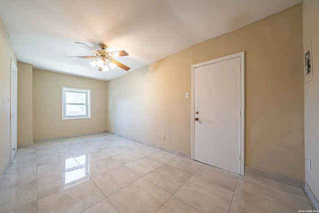 an empty room with windows and chandelier fan