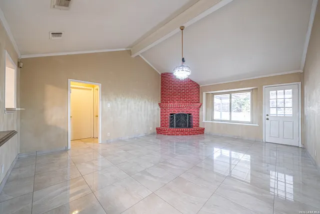 a view of an empty room with window and chandelier fan