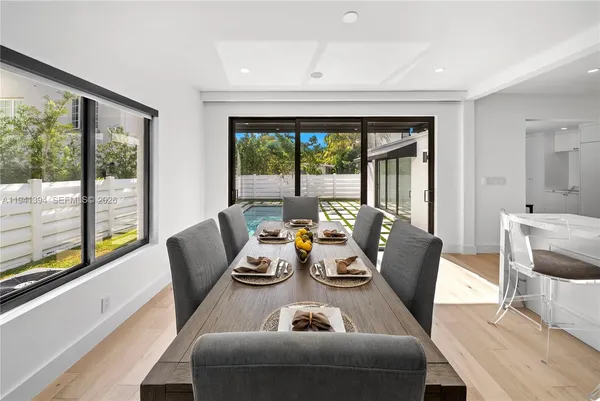 a dining room with furniture a large window and a potted plant