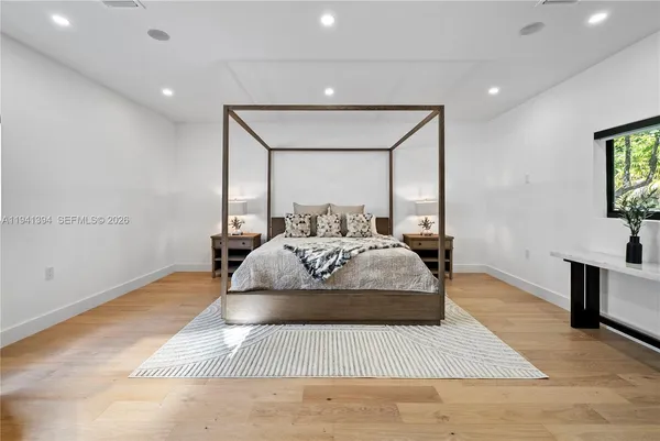 a bedroom with a large bed and a potted plant on dresser