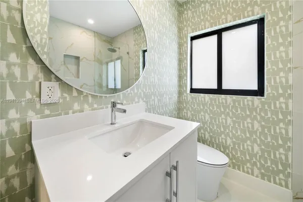 a bathroom with a sink a toilet and mirror