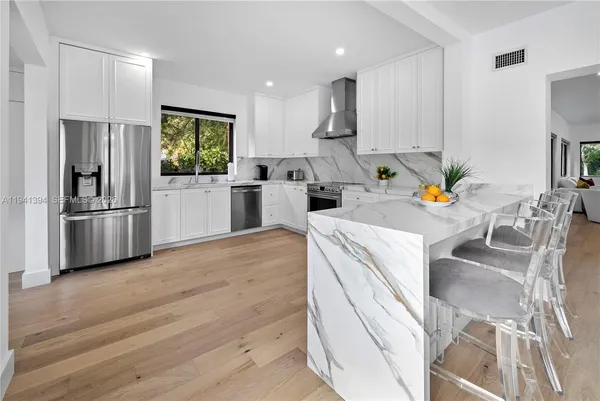 a kitchen with stainless steel appliances a refrigerator a sink a stove a dining table and chairs