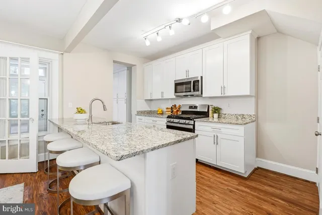 a kitchen with stainless steel appliances granite countertop a sink a stove a refrigerator cabinets and a dining table