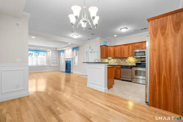 a kitchen with stainless steel appliances granite countertop a refrigerator a oven a sink dishwasher and white cabinets with wooden floor