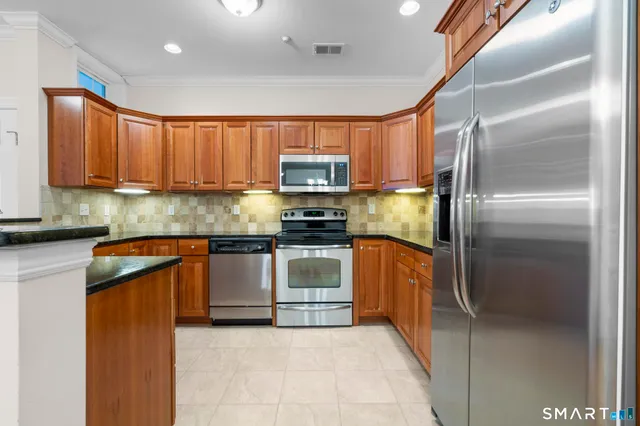 a kitchen with granite countertop a refrigerator and a stove top oven