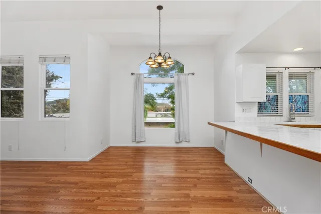 a view of a hallway with wooden floor and a bathroom