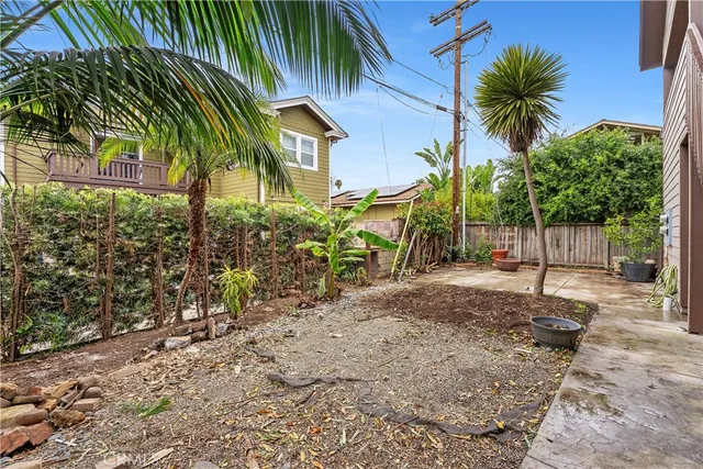 a view of a palm trees front of house with wooden fence