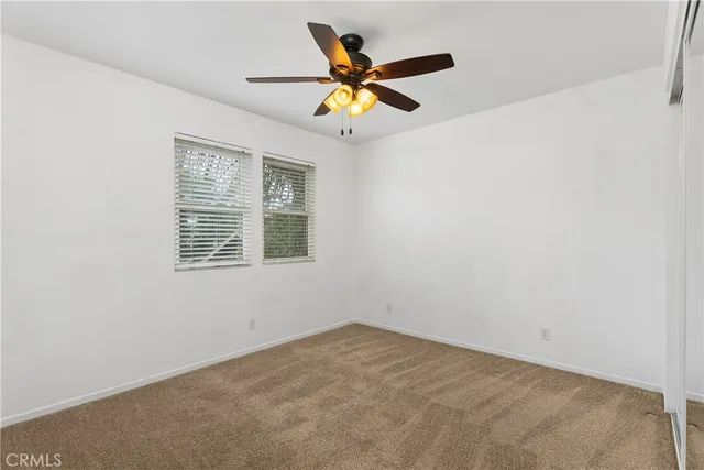 an empty room with a ceiling fan and window
