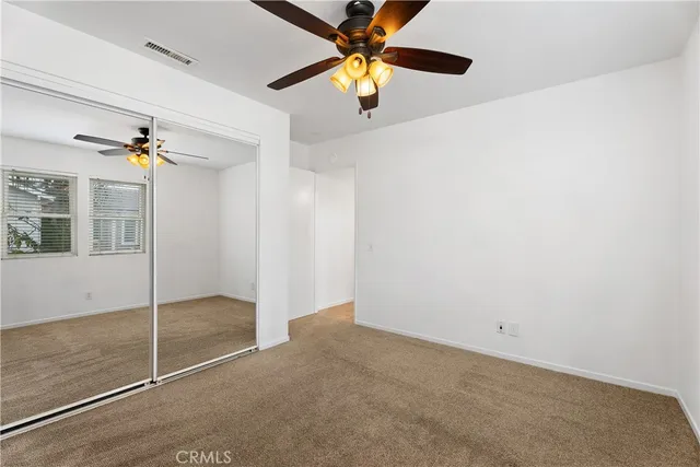 en empty room with closet and a chandelier fan