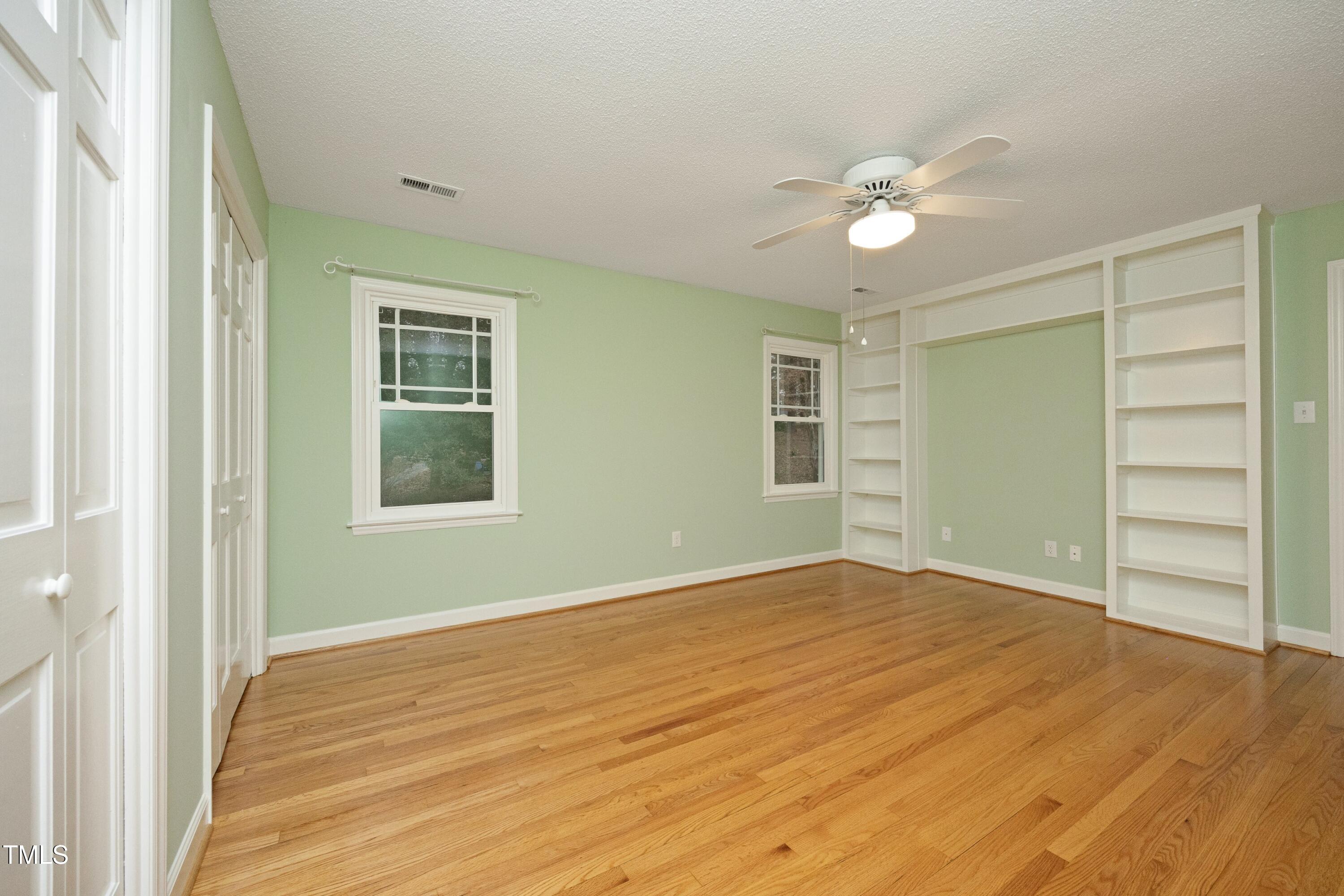 4616 Oak Park Road Raleigh, NC 27612 - Photo 31 of 63 Secondary bedroom with built-in shelves, hardwoods & ceiling fan