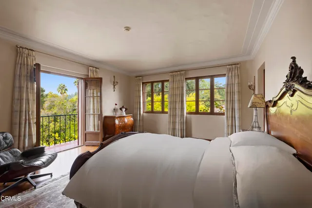 a spacious bedroom with a bed a chandelier and dresser