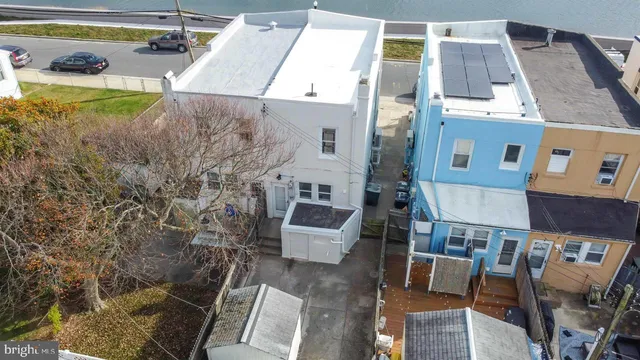 a view of a white house with a large tree and wooden fence