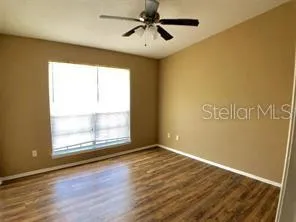 a view of an empty room with window and wooden floor