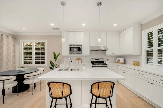 a kitchen with stainless steel appliances granite countertop a table chairs sink and cabinets