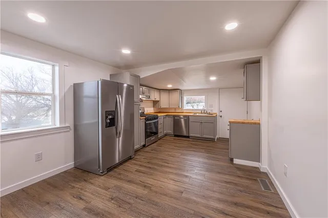 a kitchen with stainless steel appliances granite countertop a refrigerator a sink a stove and oven with wooden floor