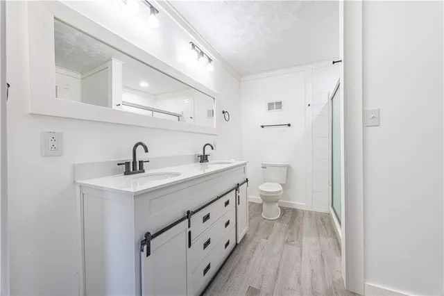 a spacious bathroom with a double vanity sink a toilet and a mirror