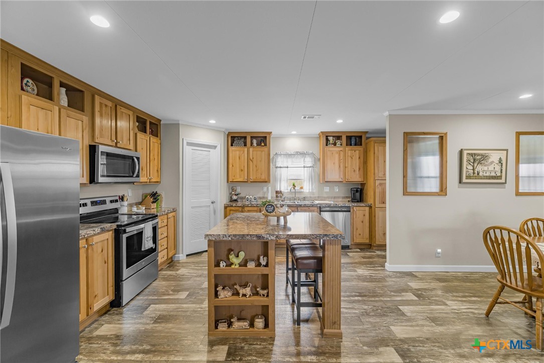2610 Wendel Road Meyersville, TX 77974 - Photo 9 of 29 a kitchen with stainless steel appliances kitchen island granite countertop a refrigerator a stove a dining table and chairs with wooden floor