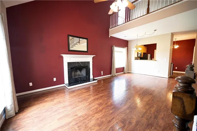 a view of an empty room with wooden floor and a fireplace