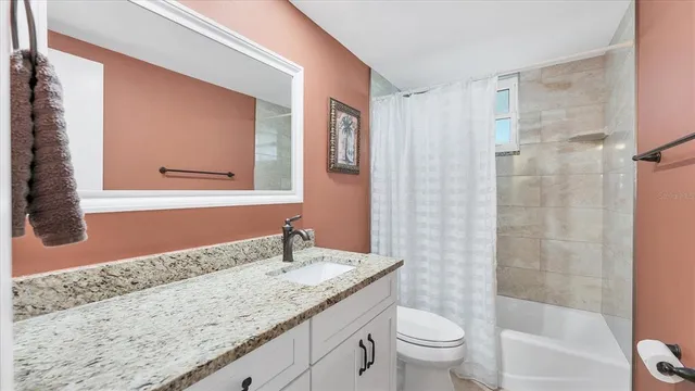 a bathroom with a granite countertop sink a toilet and shower
